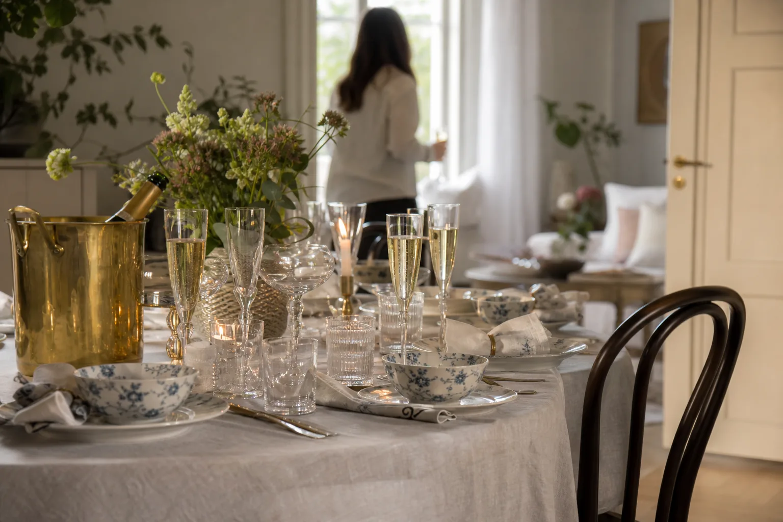 Festligt dukat bord med mönstrat porslin, champagneglas och vinkylare